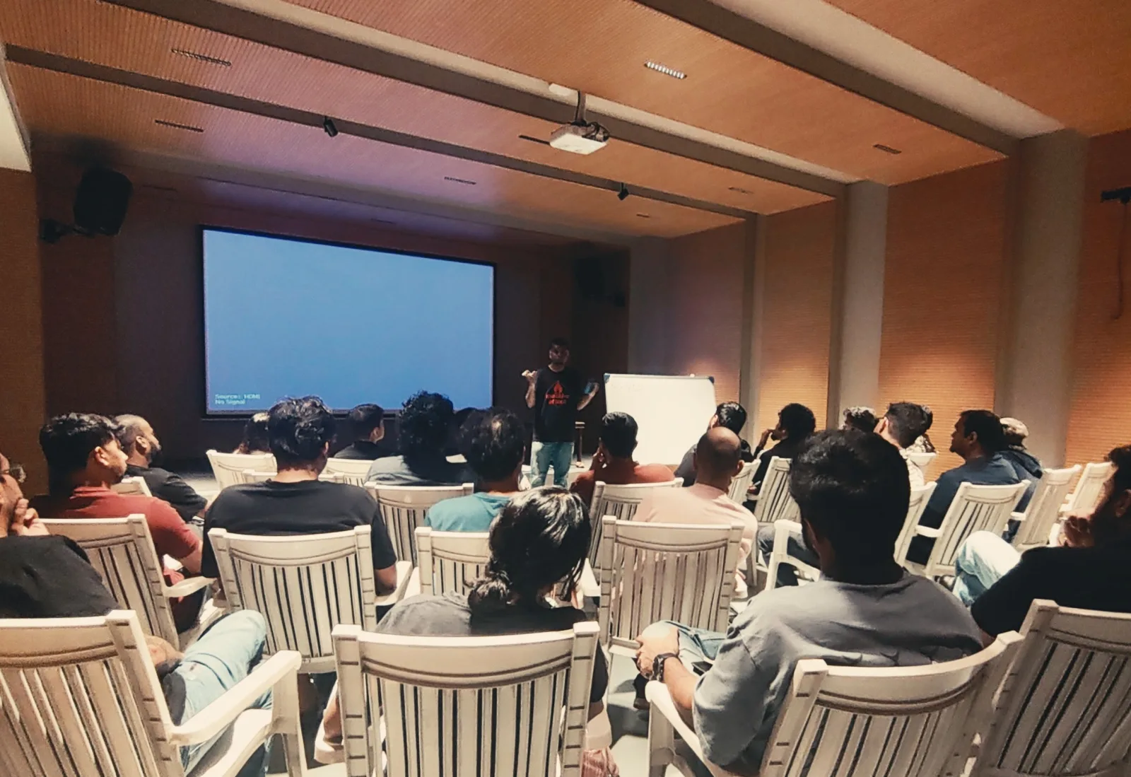 Leslie Charles speaking to a seated audience in front of a projection screen at the first workshop
